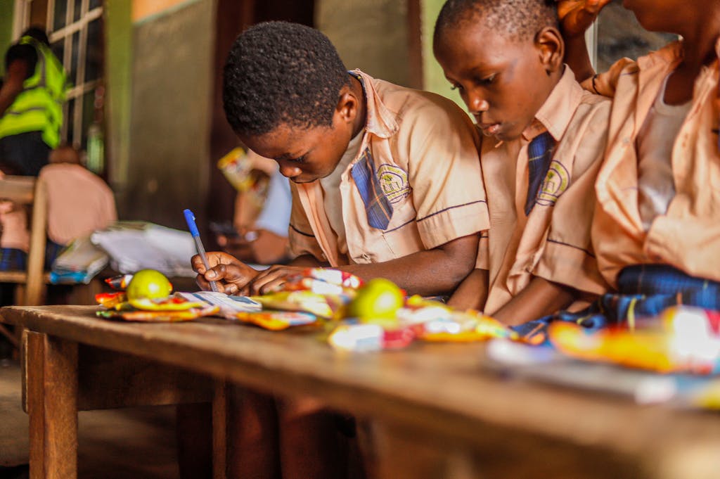Young students focused on writing and studying together in a classroom environment.