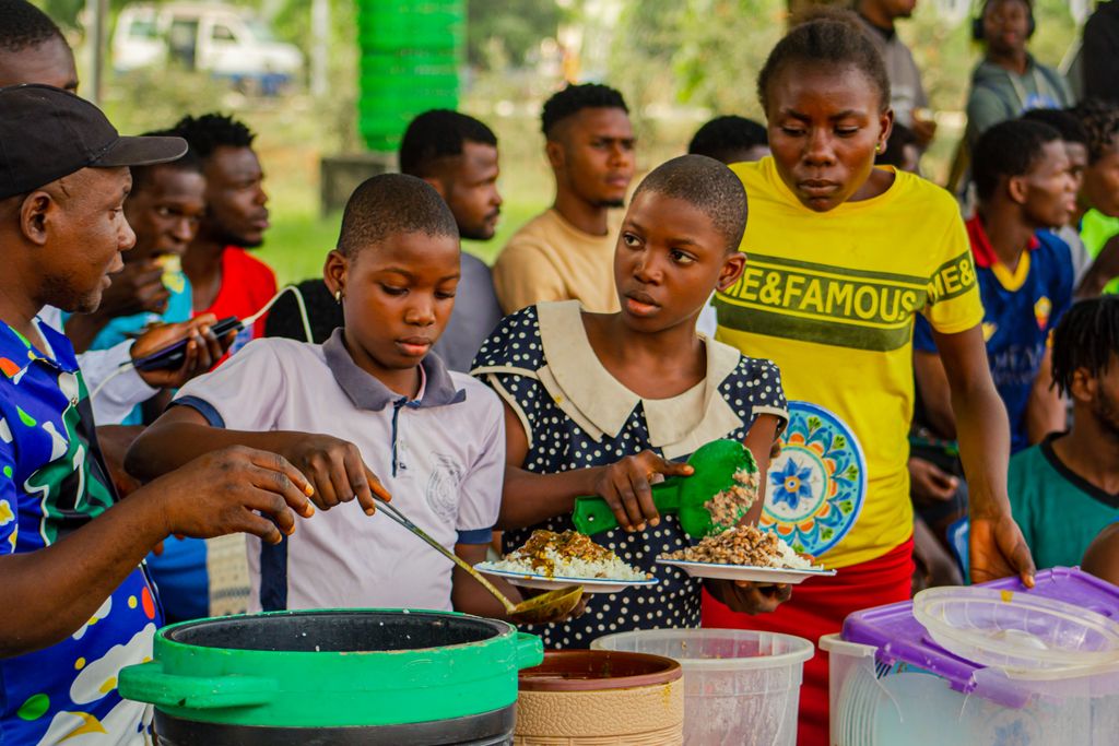 People gathered outdoors sharing and preparing a traditional meal. Vibrant cultural scene.